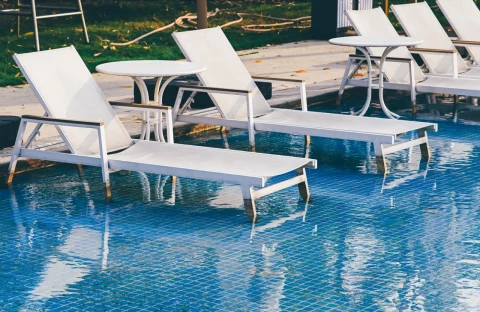 White loungers beside a pool with blue tile