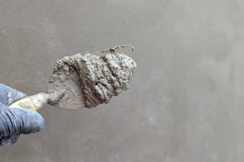 Gloved hand holding a trowel loaded with mortar