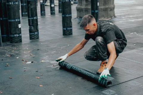 Worker rolling out a waterproofing membrane