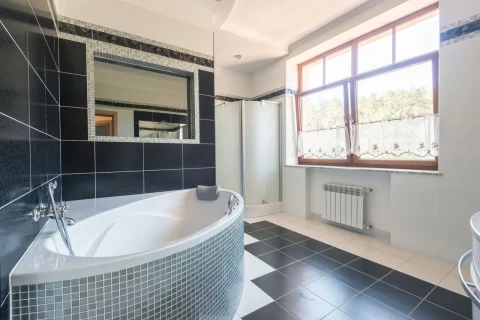 Bathroom with a corner tub and black and white floor tile