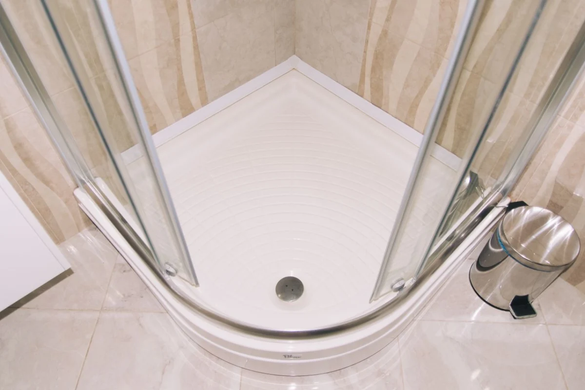 Corner shower enclosure with a white base in a tiled bathroom